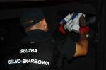 Funkcjonariusz Służby Celno-Skarbowej wyjmuje ukryte w samochodzie papierosy