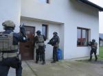 Zdjęcie przedstawia czterech funkcjonariuszy Służby Celno-Skarbowej, którzy wchodzą do budynku należącego do grupy przestępczej.