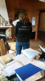 Funkcjonariuszka Służby Celno-Skarbowej podczas przeszukania. W tle segregatory, dokumenty.