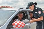 Zdjęcie przedstawia funkcjonariuszkę Służby Celno-Skarbwej wraz z siedzącymi w samochodzie dwoma kibicami, którzy jadą na mecz.