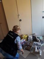 Zdjęcie przedstawia funkcjonariuszkę Służby Celno-Skarbowej i nielegalne paczki papierosów.