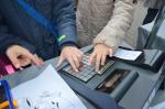 Zdjęcie przedstawia dłonie dzieci wciskające przyciski na eksponacie kasy fiskalnej znajdującej się na stanowisku KAS