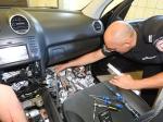 Funkcjonariusz służby celno-skarbowej wyciąga papierosy ukryte w samochodzie