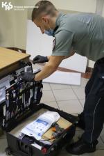 Funkcjonariusz pochylony nad walizka z przyborami techników