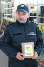 Funkcjonariusz trzyma puszkę z napisem Pomoc dla Ukrainy
