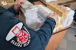 Funkcjonariusz Służby Celno-Skarbowej układa pakiety papierosów.