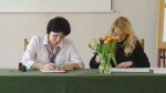 Dwie kobiety siedzą przy stole i podpisują dokumenty
