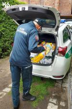 Funkcjonariusz Służby Celno-Skarbowej układa produkty w bagażniku radiowozu.