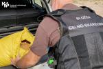 Funkcjonariusz Służby Celno-Skarbowej wyjmuje worek z krajanką tytoniową z bagażnika samochodu.
