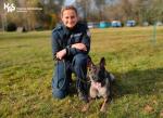 Funkcjonariusz Służby Celno-Skarbowej z psem służbowym siedzi na trawniku.