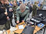 Funkcjonariusz Służby Celno-Skarbowej prezentuje zabezpieczanie śladów uczennicom w mundurze.
