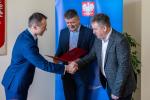 Zastępca Dyrektora Izby Administracji Skarbowej w Olsztynie, Mariusz Wesołowski składa gratulacje dwóm mężczyznom. Wymieniają uściski dłoni.