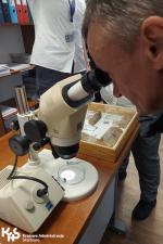 Mężczyzna ogląda materiał ułożony pod mikroskopem.