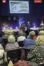 Męzczyźni i kobiety siedza na krzesełkach w sali