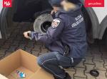 Funkcjonariuszka Służby Celno-Skarbowej wyciąga z koła pojazdu paczki papierosów