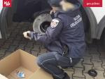 Funkcjonariuszka Służby Celno-Skarbowej wyjmuje papierosy z koła pojazdu.